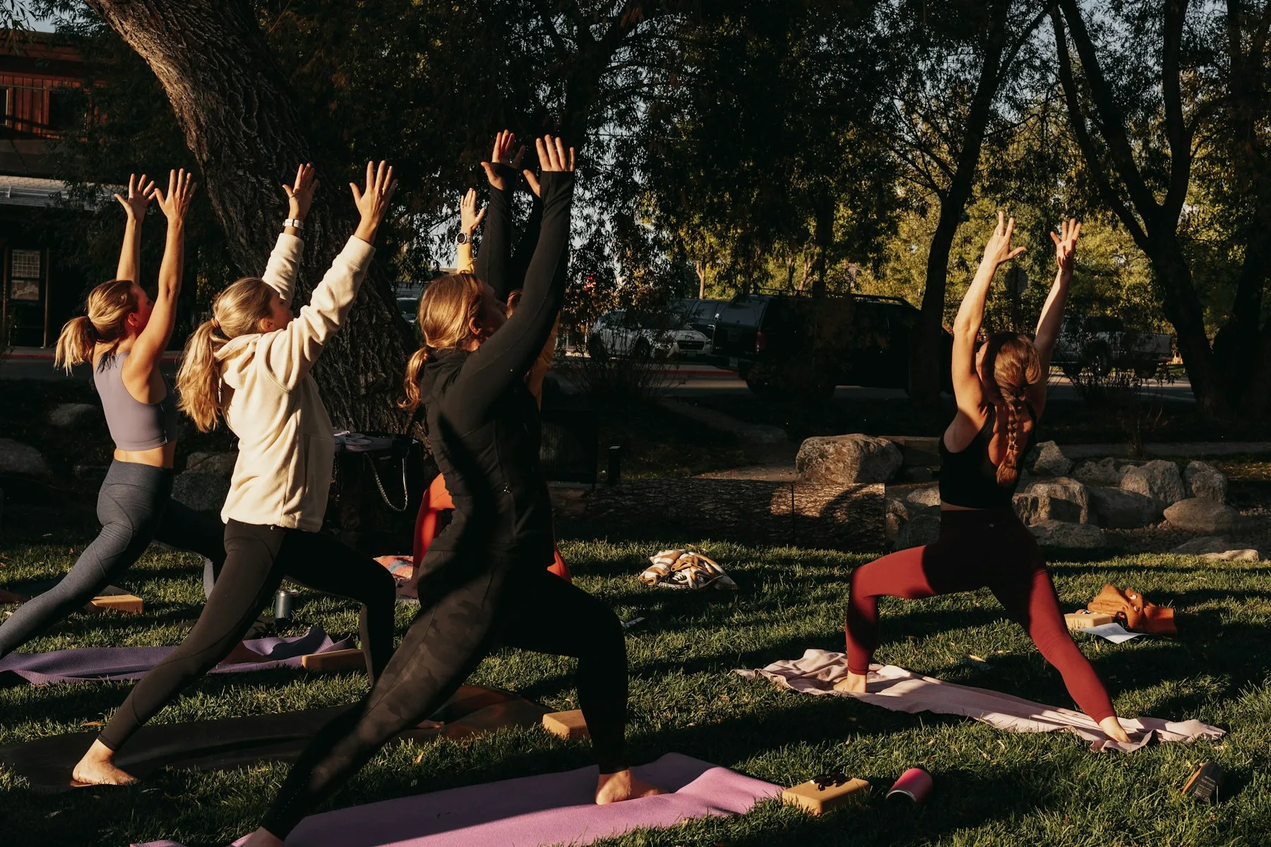 Cours collectif de yoga en plein air dans un parc, avec tapis et professeur devant le groupe